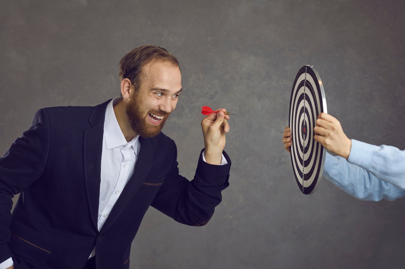 Businessman Aiming Dart at Dartboard as Metaphor for Setting Goals and Objectives